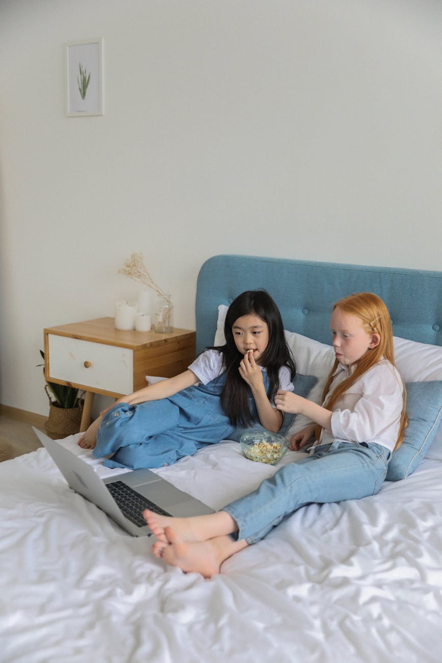 Friends laughing while watching a movie on a couch.