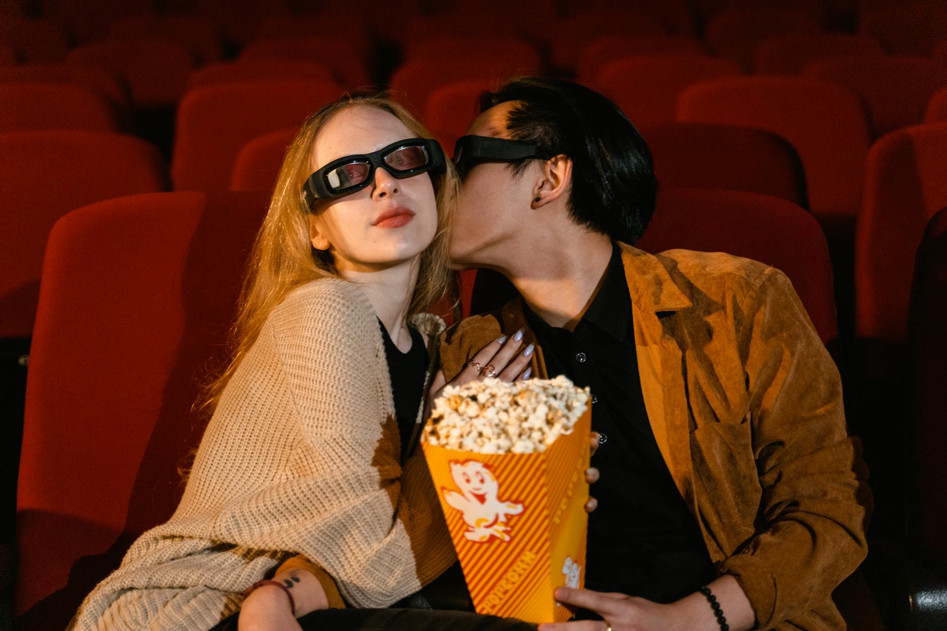 Couple cuddling on the couch watching a movie on a laptop.